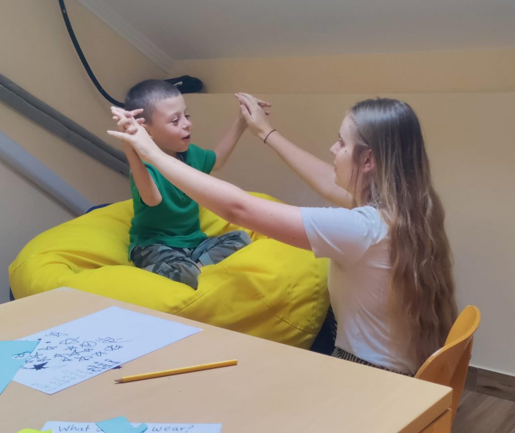 Hannah supporting a young child with movement therapy.